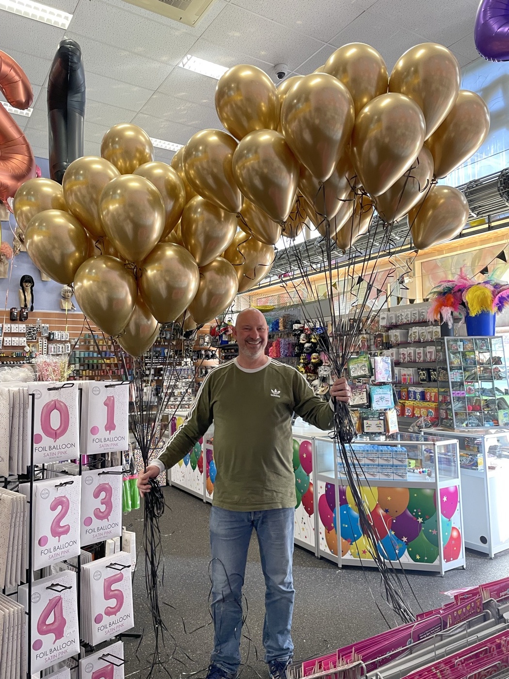 Rinus Koorn in de winkel met een tros gouden ballonnen